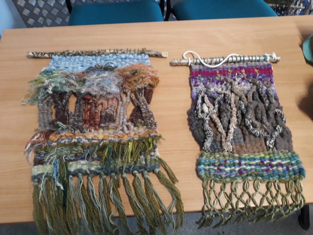 Two examples of peg loom weaving lying on a table.