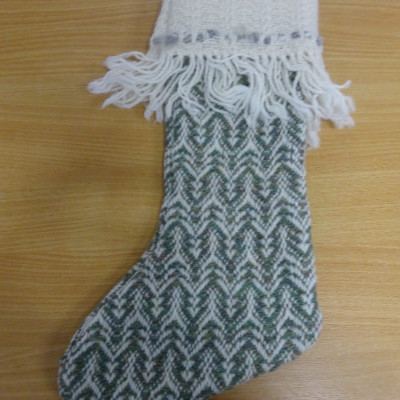 Handwoven Christmas stocking with motifs resembling Christmas trees in green and white