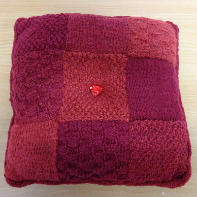 Red patchwork cushion made of knitted squares