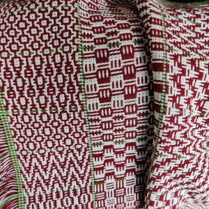 Woven fabric with various patterns, in red and white, with a some green.