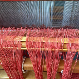 Loom with coral-coloured yarn ready for weaving